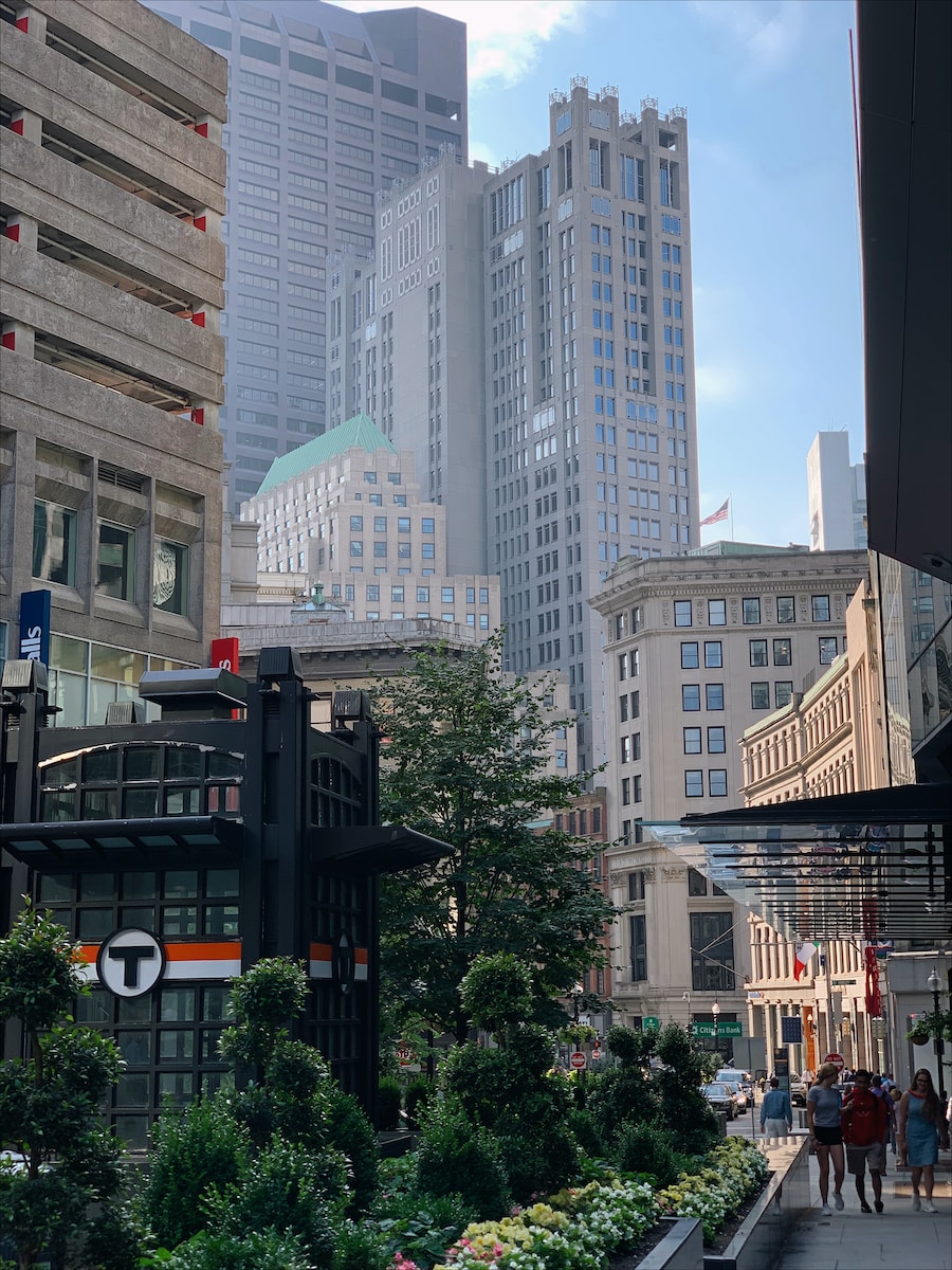 a group of people walking down a street next to tall buildings