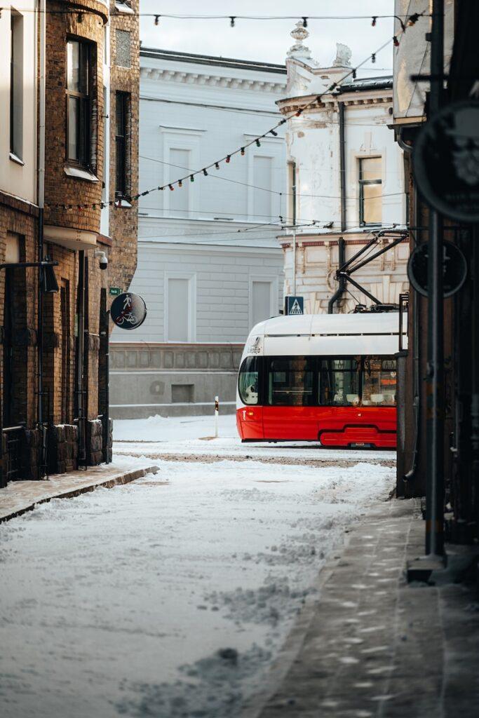 a red and white bus driving down a snow covered street