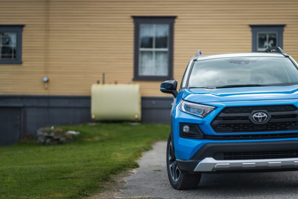 a blue toyota rav parked in front of a house